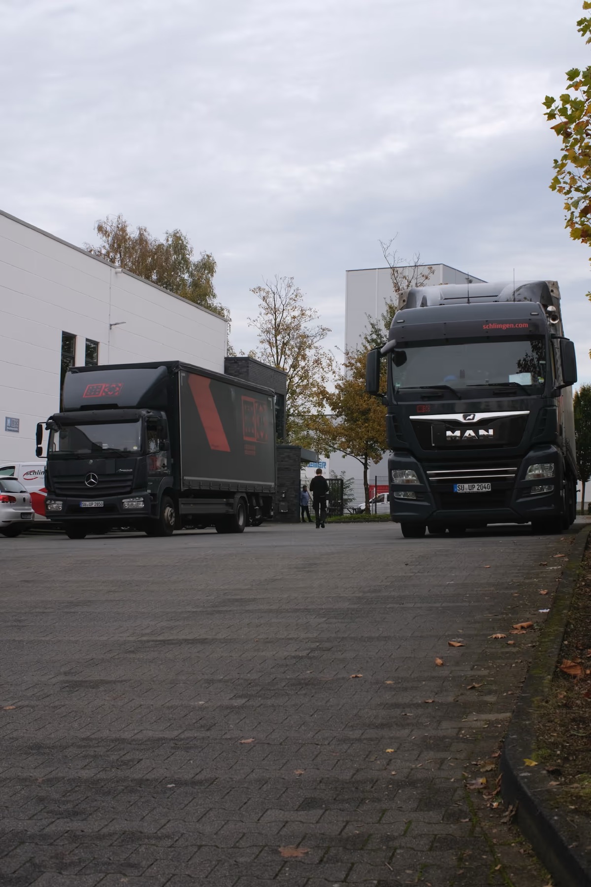 Zwei Schlimgen-Lkw auf dem Betriebshof, eine Person geht auf sie zu