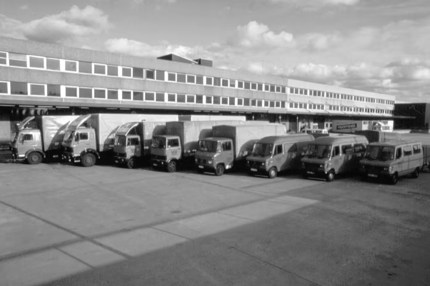 Historisches Schwarzweißfoto: Lkw-Flotte vor der Halle