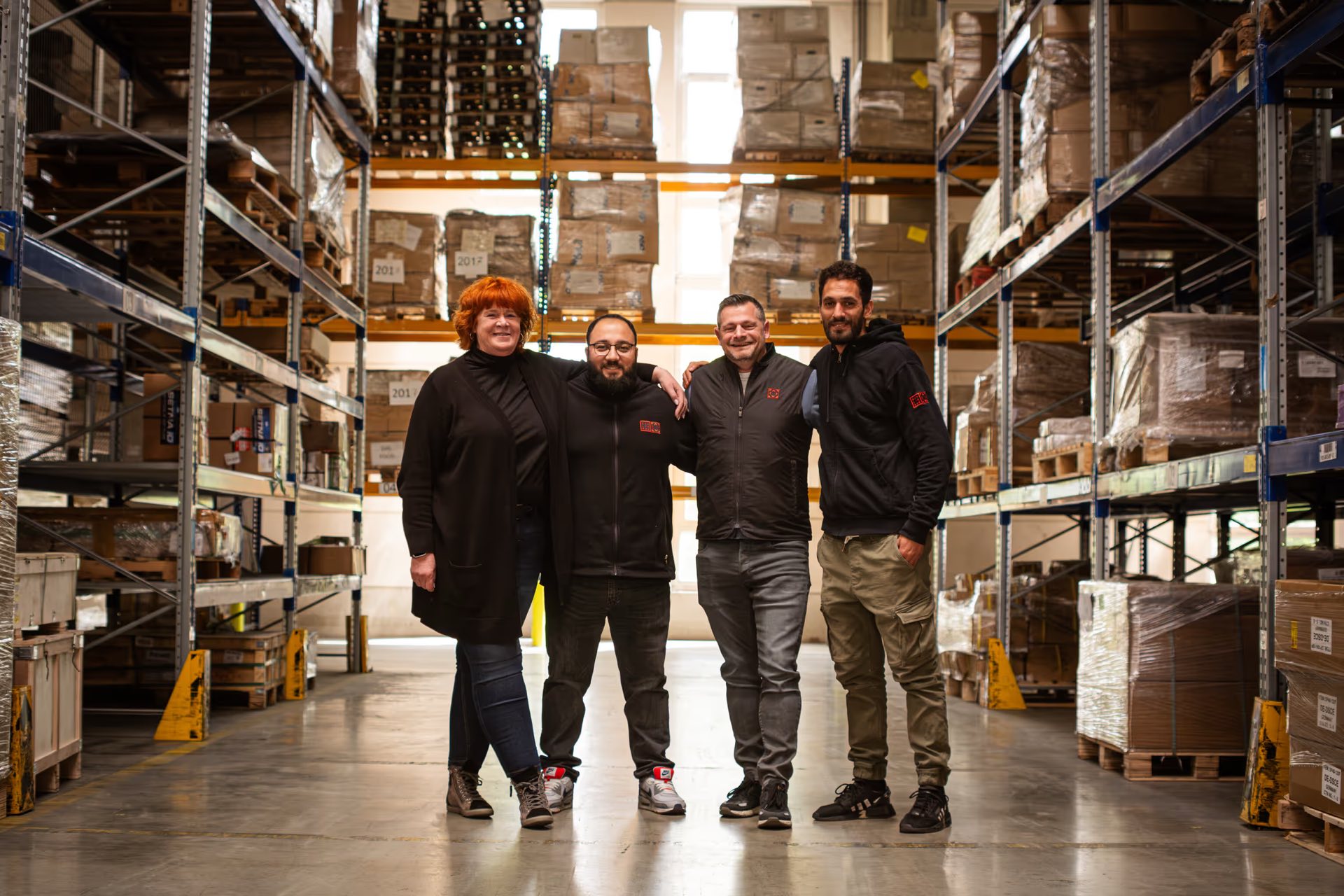 Vier Kolleginnen und Kollegen von Schlimgen Logistics stehen nebeneinander im Lager in Troisdorf